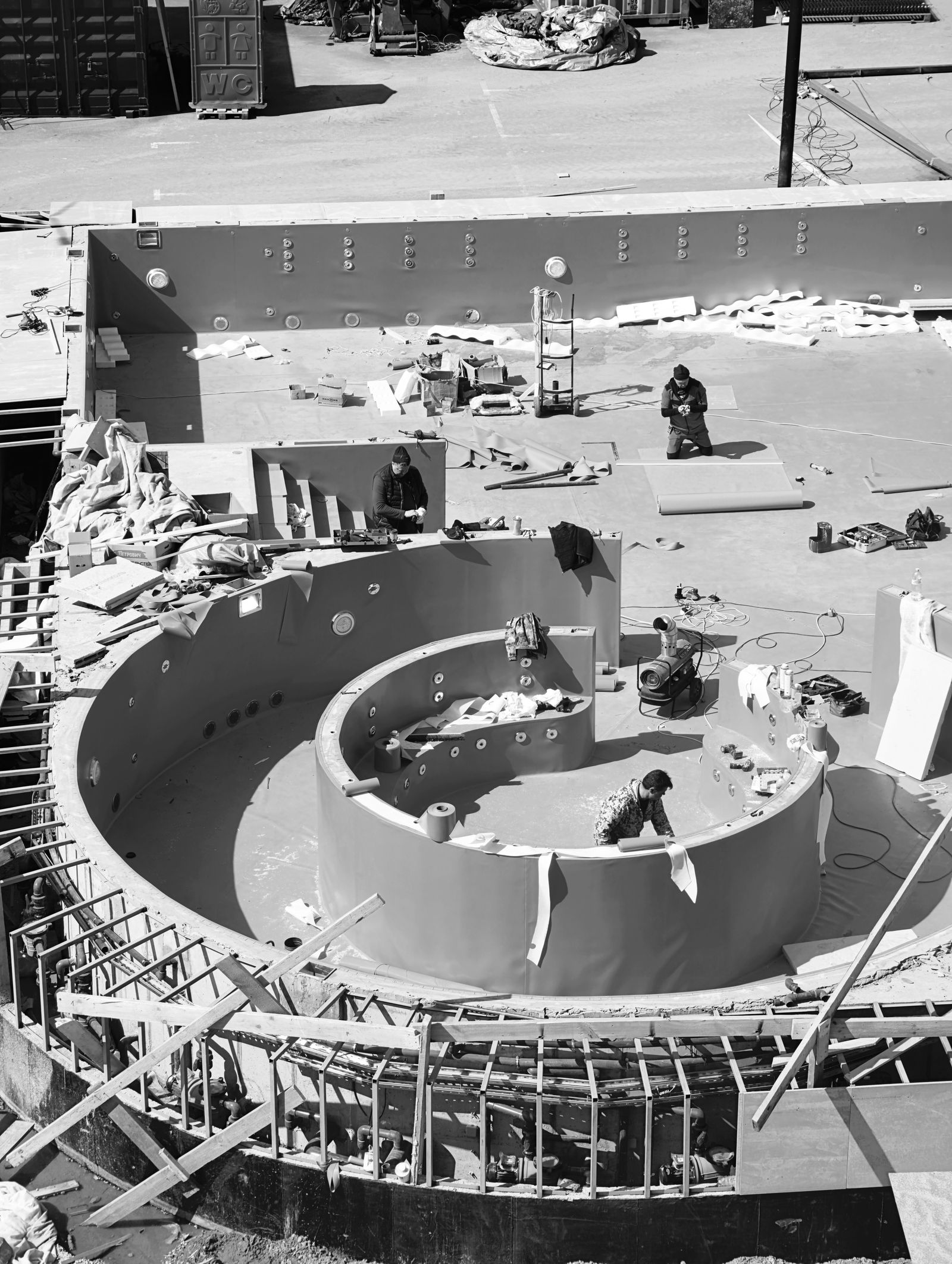 Construction crew at work in the shell of a new curved swimming pool